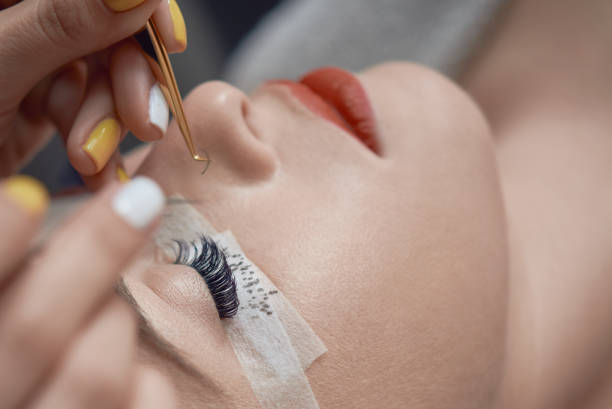 hands of an eyelash tech adding eyelash extension to a woman with eyes closed